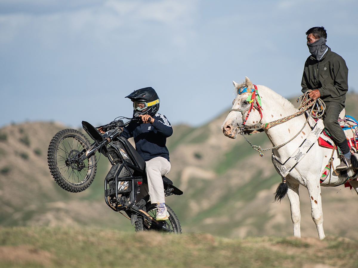 Electric dirt bike rider riding beside a horse on a desert trail